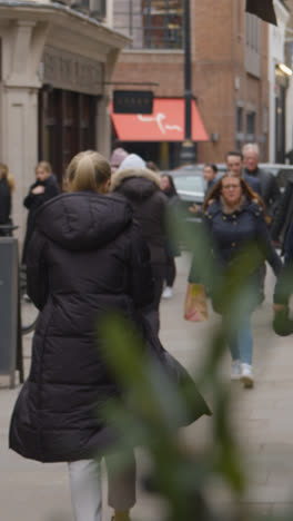 Vertical-Video-Pull-Focus-Shot-Of-Shops-And-Restaurants-With-People-On-Avery-Row-In-Mayfair-London-UK